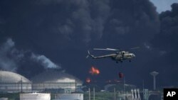 Helikopter pemadam kebakaran menjatuhkan air di Matanzas Supertanker Base untuk memadamkan api akibat disambar petir sehari sebelumnya, di Matanzas, Kuba, Sabtu, 6 Agustus 2021. (AP/Ramon Espinosa)