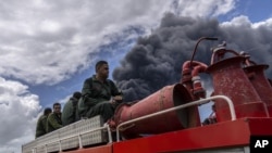 Los bomberos se desplazan en un camión dentro de la base de superpetroleros de Matanzas para sofocar un incendio que comenzó durante una tormenta eléctrica, en Matanzas, Cuba, el domingo 7 de agosto de 2022.