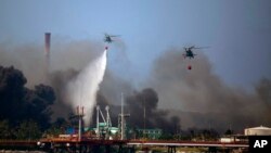 Helicopters hauling water fly over the Matanzas Supertanker Base, as firefighters and specialists work to quell the blaze which began during a thunderstorm, in Matanzas, Cuba, Aug. 8, 2022. 