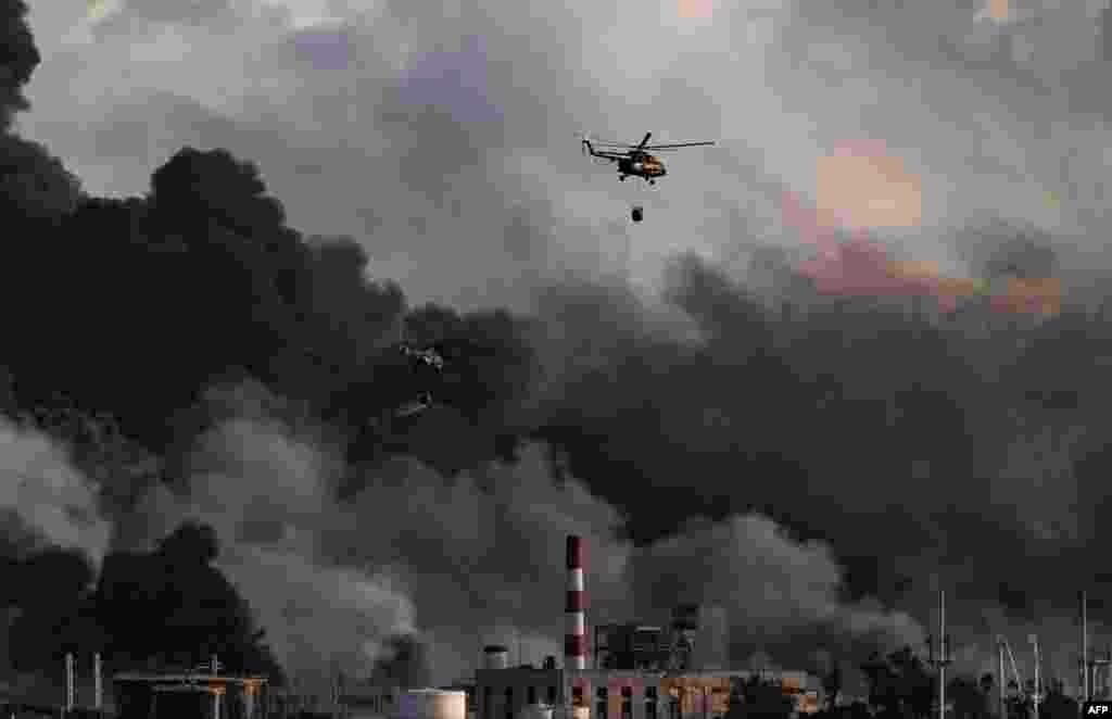 Un helicóptero de los bomberos lanza agua sobre un enorme incendio en un depósito de combustible provocado por un rayo en Matanzas, Cuba, el 8 de agosto de 2022.&nbsp; (Foto de YAMIL LAGE / AFP)