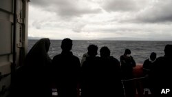 Migrants stand on the deck of the Ocean Viking rescue ship, in the Strait of Sicily, in the Mediterranean Sea, Nov. 5, 2022. 