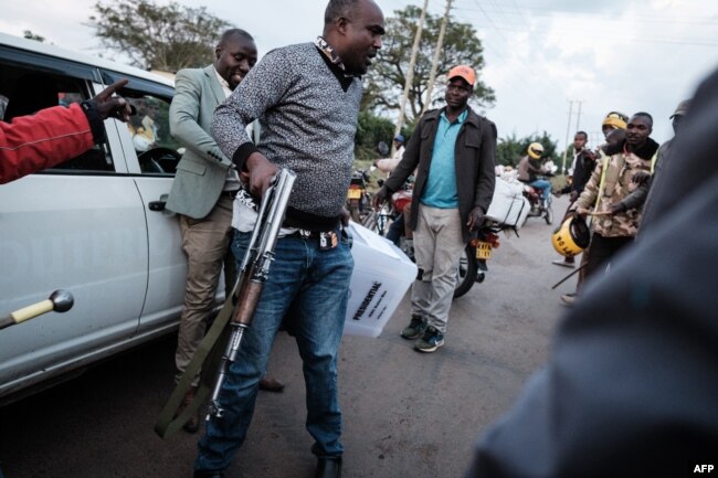 A police officer tries to protect a presidential ballot box near the tallying center in Kilgoris, Kenya, Aug. 8, 2022.