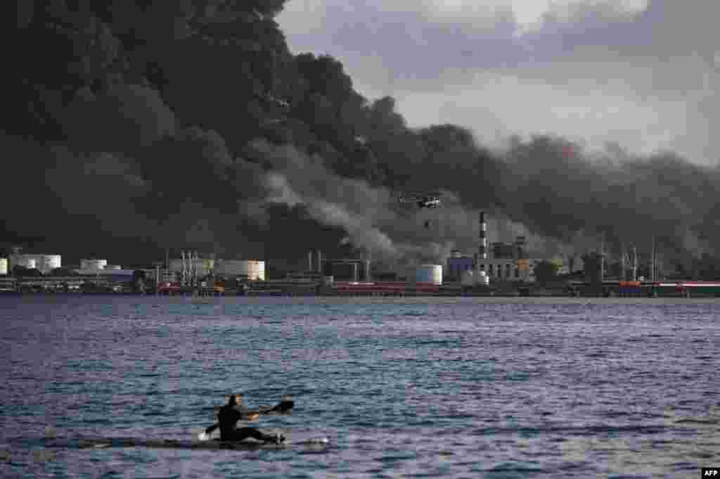 Un helicóptero busca agua en la bahía de Matanzas. El incidente se produjo la noche del viernes cuando un rayo impactó en un tanque de combustible que tenía un 50% de su capacidad de llenado &mdash;52.000 metros cúbicos&mdash; de crudo.&nbsp;(Foto de YAMIL LAGE / AFP)