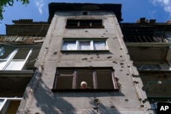 Ida Svystunova, 89, looks out the damaged room adjoining her apartment from a May rocket attack in Sloviansk, Donetsk region, eastern Ukraine, Aug. 7, 2022.