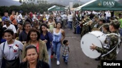 Venezuelans pass Colombian soldiers as they cross into Colombia over the Simon Bolivar international bridge in Cucuta, Colombia, Aug. 13, 2016.