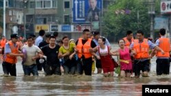 Polisi di kota Chengdu, provinsi Sichuan, China membantu para warga yang terjebak banjir (9/7). 