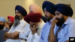 FILE - Members of the Sikh Temple of Wisconsin listen at a news conference in Oak Creek, Wisconsin, on Monday, Aug. 6, 2012, the day after a gunman walked into the temple and and opened fire, killing six and another who died later. 