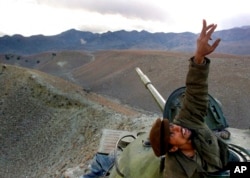 FILE - An Afghan anti-Taliban fighter pops up from his tank to spot a U.S. warplane bombing the al-Qaida fighters in the White Mountains of Tora Bora in Afghanistan, Dec. 10, 2001.