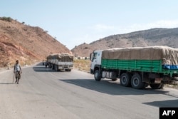 FILE - A man walks next to a convoy of trucks on their way to Tigray in the village of Erebti, Ethiopia, June 9, 2022.