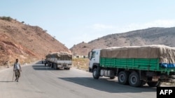 FILE - A man walks next to a convoy of trucks on their way to Tigray in the village of Erebti, Ethiopia, June 9, 2022.