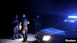 烏克蘭城市克拉馬托爾斯克市的警察宵禁開始後在夜間巡邏時檢查一名行人的證件（2022年8月5日）