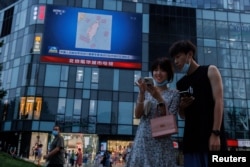 北京市民在觀看街頭電子屏幕上官媒央視播放的中國軍隊在台灣附近舉行實彈軍演的報導。（2022年8月3日）