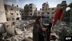 Una mujer palestina cuelga la ropa que recogió de los escombros el 8 de agosto de 2022 frente a su casa, gravemente dañada por los ataques aéreos israelíes la semana pasada en la ciudad de Gaza, horas después de que entrara en vigor un alto el fuego entre Israel y los militantes palestinos.