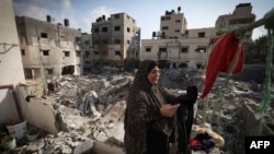 A Palestinian woman hangs clothes she picked from the rubble on August 8, 2022, outside her home damaged in Israeli air strikes last week in Gaza city, hours after a cease fire took effect between Israel and Palestinian militants.