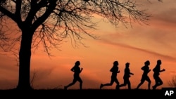 FILE - High school students run at sunset as they practice for the track and field season Monday, Feb. 28, 2022, in Shawnee, Kan. New research hints that even simple exercise just might help fend off memory problems. (AP Photo/Charlie Riedel, File)