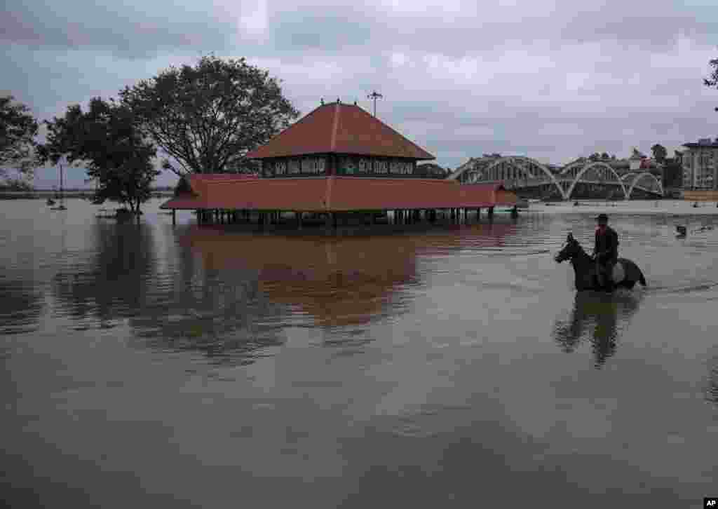 A youth rides a horse past a partially submerged Hindu temple through the waters of River Periyar which flooded due to heavy rains in Kochi, Kerala state, India, Aug. 2, 2022.