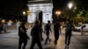 Activists from the collective 'On the Spot' walk by the Arc de Triomphe, during a night of action where they will extinguish the lights on dozens of storefronts in Paris, July 29, 2022.