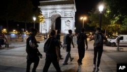 Activists from the collective 'On the Spot' walk by the Arc de Triomphe, during a night of action where they will extinguish the lights on dozens of storefronts in Paris, July 29, 2022.