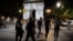 Activists from the collective 'On the Spot' walk by the Arc de Triomphe, during a night of action where they will extinguish the lights on dozens of storefronts in Paris, July 29, 2022.