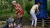Residents fill up water bottles in a park near their apartments in Sloviansk, Donetsk region, eastern Ukraine, Aug. 6, 2022. The city has no running water as artillery and missile strikes have downed power lines and punched through water pipes.
