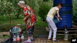 Residents fill up water bottles in a park near their apartments in Sloviansk, Donetsk region, eastern Ukraine, Aug. 6, 2022. The city has no running water as artillery and missile strikes have downed power lines and punched through water pipes.