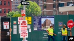 Construction workers help direct traffic outside a residential and commercial building under construction on the Lower East Side of Manhattan, as hiring boom continued last month, Aug 4, 2022. 