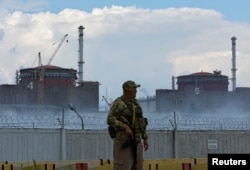 FILE - A serviceman with a Russian flag on his uniform stands guard near the Zaporizhzhia nuclear power plant outside the Russian-controlled city of Enerhodar, in the Zaporizhzhia region, Ukraine, Aug. 4, 2022.