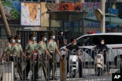 在美国驻北京大使馆外守卫的保安看一队武警走过。（2022年8月3日）