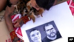 FILE - An Indigenous girl colors a poster with images of slain British journalist Dom Phillips, left, and Indigenous expert Bruno Pereira in Brasilia, Brazil, June 23, 2022. 