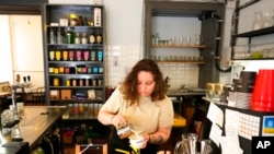 FILE - Ukranian refugee Lisa Himich prepares a coffee at a shop where she works, July 15, 2022, in Prague, Czech Republic.