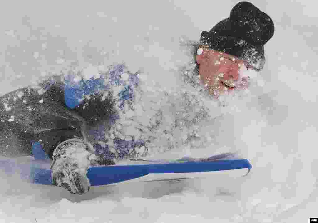 Một người đàn ông trượt xuống một ngọn đồi phủ đầy tuyết ở tây bắc thủ đô Washington, Mỹ. Tuyết rơi dày từ 10-15 cm qua đêm ở thành phố khiến trường học và văn phòng chính phủ đóng cửa