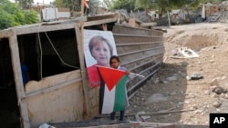 A Bedouin child stands in front of a picture of German Chancellor Angela Merkel ahead of her expected visit to Israel on Oct. 3, 2018, in the West Bank Bedouin community of Khan al-Ahmar, Oct. 2, 2018. 