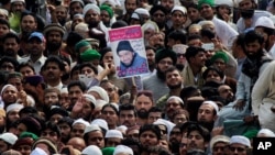 People hold the photo of police officer Mumtaz Qadri, the convicted killer of a former governor, during his funeral, in Rawalpindi, Pakistan, Tuesday, March 1, 2016. 
