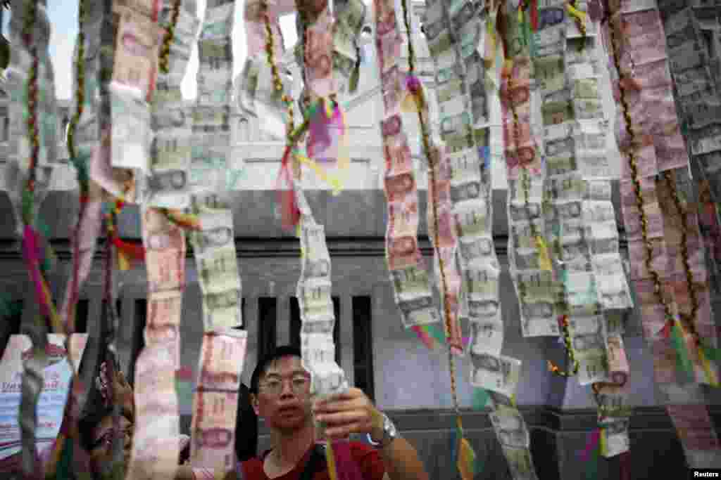 People decorate a temple with Thai banknotes ahead of the Chinese Lunar New Year celebrations in Bangkok&#39;s Chinatown, Thailand. 