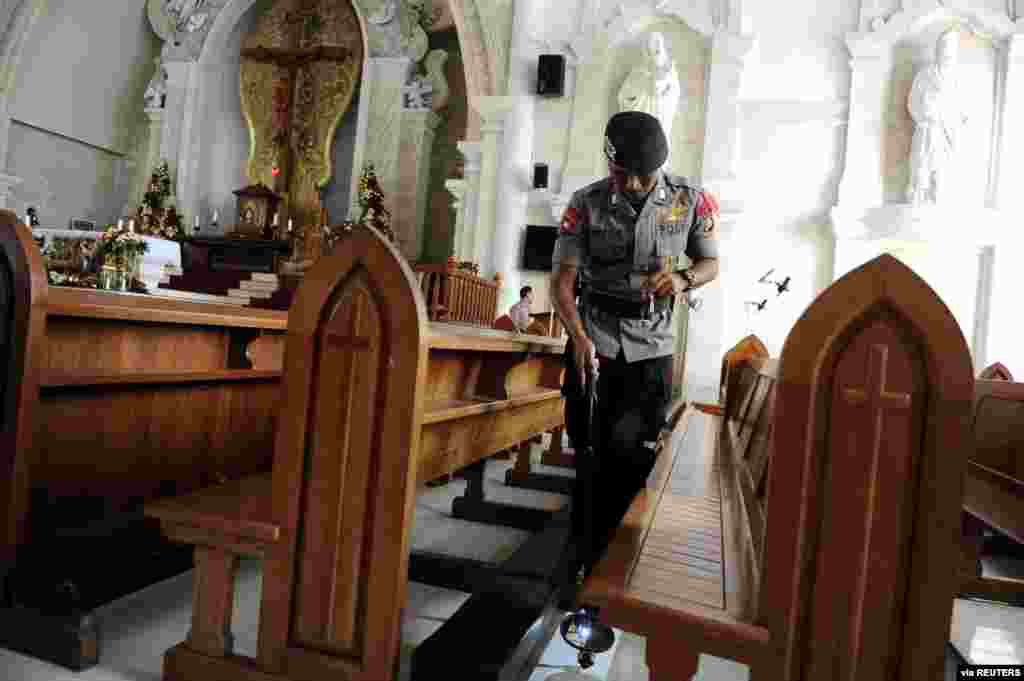 Police officer checks during a security sweep ahead of the Christmas Eve mass at the Holy Spirit Catholic Church of Denpasar Cathedral, Bali, Indonesia, in this photo taken by Antara Foto. 