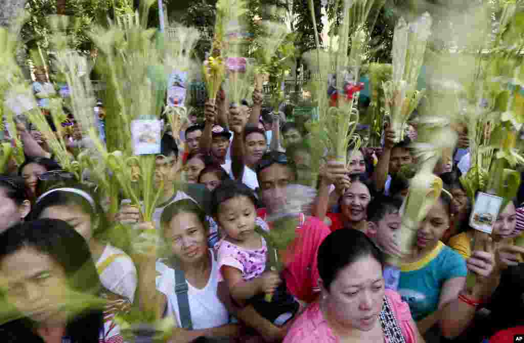 Roman Catholic devotees wave palm fronds to be blessed by a priest to commemorate Palm Sunday which marks the beginning of Holy Week at the Redemptorist Church in Baclaran, south of Manila, Philippines.