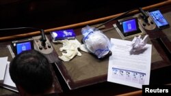 A face mask and protective gloves are seen on a lawmaker's desk during a session of Italy's Senate, the upper house of the country's parliament, on the spread of the coronavirus, in Rome, Italy, March 26, 2020.