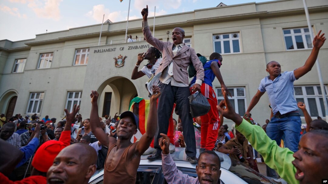 Zimbabweans celebrate outside the parliament building immediately after hearing the news that President Robert Mugabe had resigned, in downtown Harare, Zimbabwe, Nov. 21, 2017. 