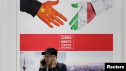 资料图片：在中国北京举行的中国国际服务贸易博览会上，一名男子在一张写有“中国在佛罗伦萨遇见欧洲”的海报旁边接听电话(2019年5月28日）