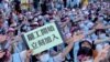 An EVA Air flight attendant holds up a sign which reads: "Strike begins, join immediately" during a protest at the EVA Air headquarters in Taoyuan, Taiwan, Friday, June 21, 2019. 