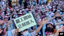 An EVA Air flight attendant holds up a sign which reads: "Strike begins, join immediately" during a protest at the EVA Air headquarters in Taoyuan, Taiwan, Friday, June 21, 2019. 