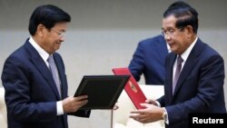 Laos' Prime Minister Thongloun Sisoulith (L) exchanges documents with his Cambodian counterpart Hun Sen after a signing ceremony at the Peace Palace in Phnom Penh, Cambodia, September 12, 2019.