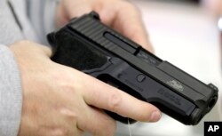 FILE - David Foley holds a handgun while shopping at the Spring Guns and Ammo store on Jan. 4, 2016, in Spring, Texas.