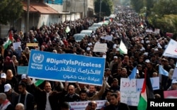 FILE - Palestinian employees of the United Nations Relief and Works Agency (UNRWA) hold signs during a protest against a U.S. decision to cut aid, in Gaza City, Jan. 29, 2018.