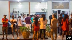 People stand in the street after nightclubs were closed by authorities in Havana, Cuba, early Saturday after the death of Fidel Castro, Nov. 26, 2016. 