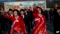 North Koreans dance together beneath a mosaic painting of the late leader Kim Il Sung during a mass folk dancing gathering in Pyongyang, April 11, 2013.