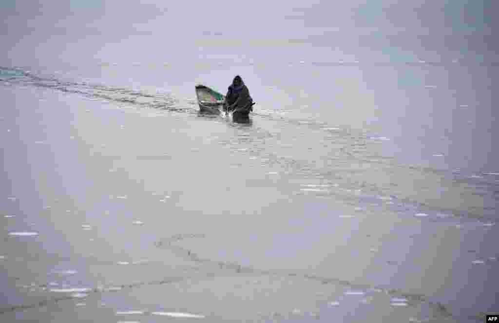 인도&nbsp;스리나가르의 &#39;달&#39; 호수에서 카슈미르 출신의 뱃사공이 길을 만들기 위해 얼음을 깨고 있다.
