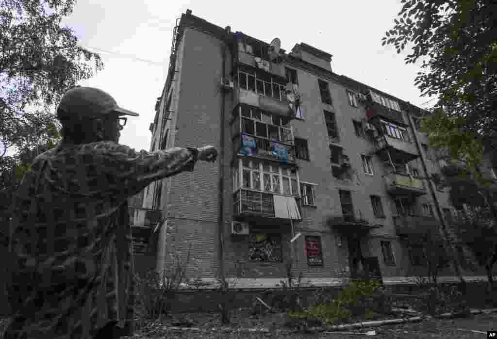 A resident shows an apartment building damaged by a mortar attack by Ukrainian government troops in Slovyansk, eastern Ukraine, June 9, 2014.