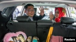 Wali Kota Bandung Ridwan Kamil, calon Gubernur Jawa Barat, dan istrinya, Atalia Kamil, melambaikan tangan ke para wartawan dari dalam mobil di Bandung, 20 Januari 2018. (Foto: Antara via Reuters)