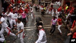 Revelers run around Nunez del Cubillo's fighting bulls on the Estafeta corner during the seventh running of the bulls at the San Fermin Festival, in Pamplona, northern Spain, Wednesday, July 13, 2016.